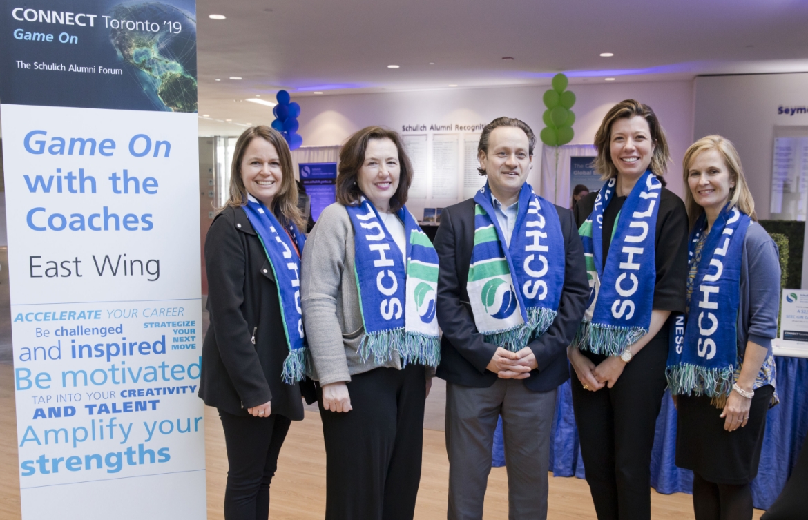 Five alumni posing for the camera wearing Schulich scarves.