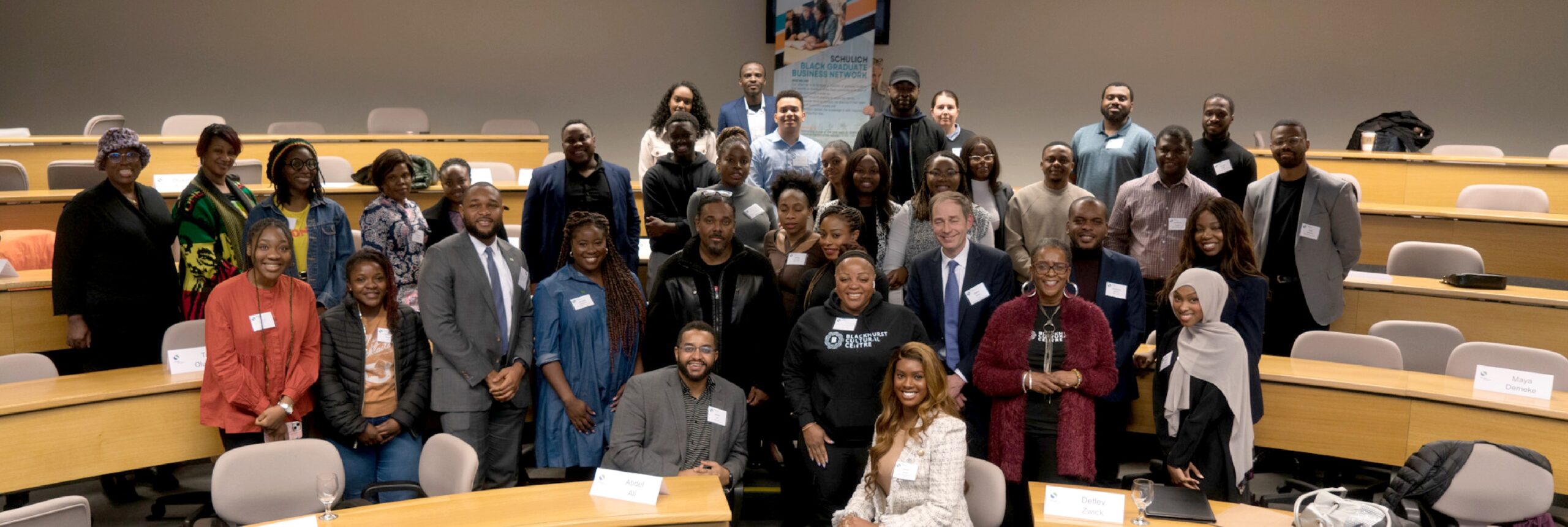 A large group of alumni standing with Dean Zwick in a Schulich classroom for event with the Schulich Black Graduate Business Network.