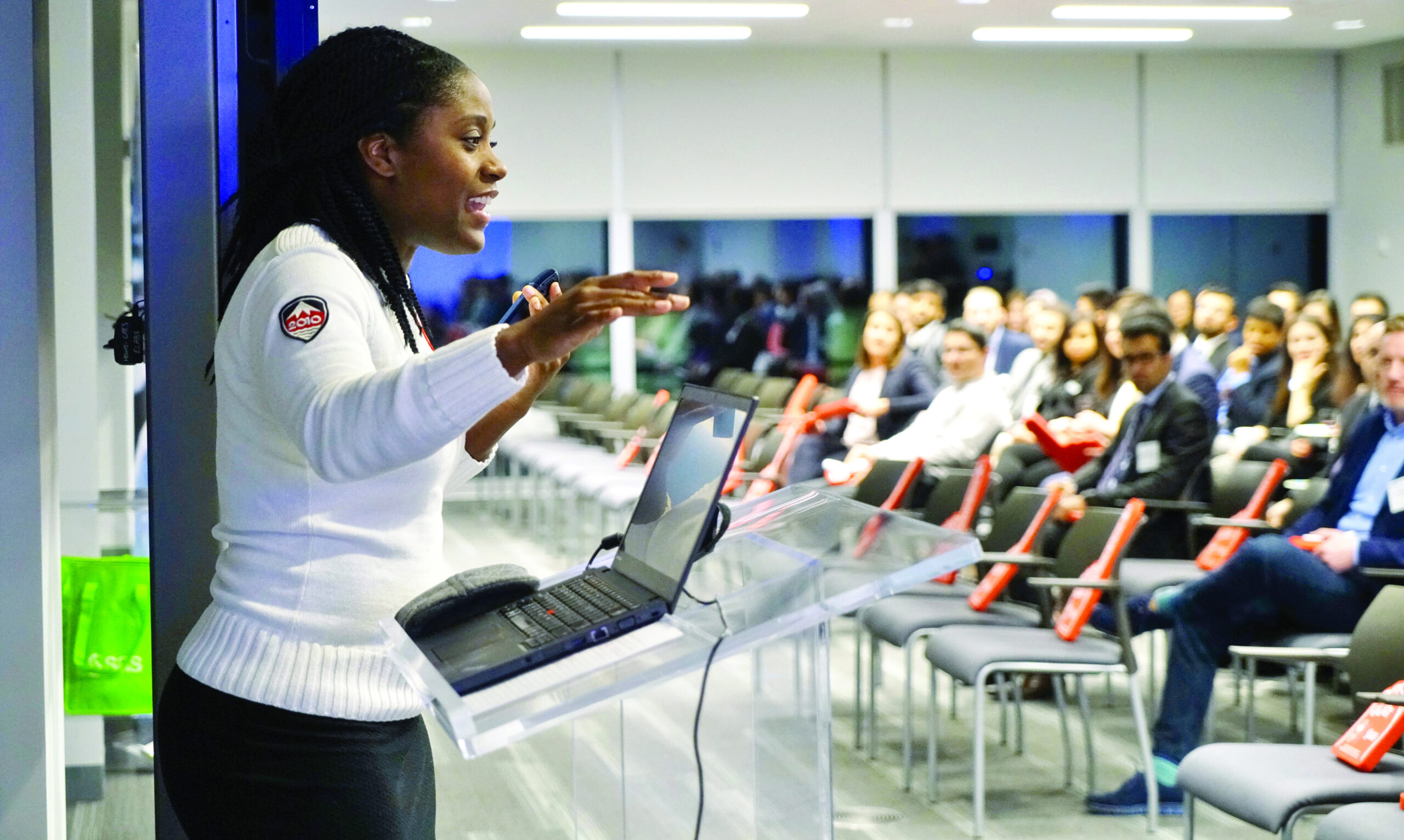 A woman standing at a podium speaking to an audience.